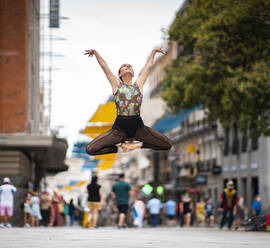 Elegant ballet dancer dancing with hand raised on street in city - JCCMF00136