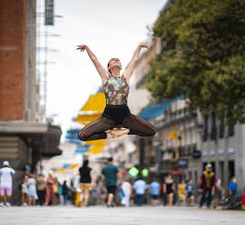 Elegante Balletttänzerin tanzt mit erhobener Hand auf der Straße in der Stadt - JCCMF00136
