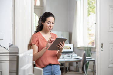 Female professional using digital tablet while standing in office - FKF03881