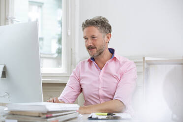 Reifer Geschäftsmann, der einen Computer bei der Arbeit im Büro benutzt - FKF03907