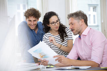 Smiling male and female colleagues discussing in meeting at office cabin - FKF03947