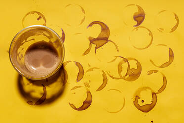 Coffee cup on coffee stained yellow table - GEMF04451