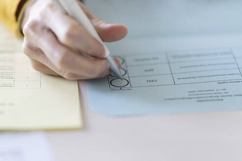 Close-up of woman filling voting ballot at home - CHPF00732