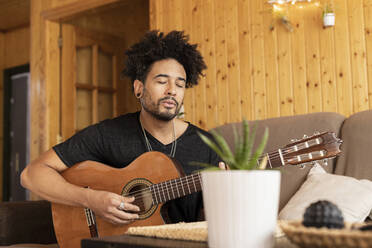 Mann singt und spielt Gitarre zu Hause - LJF01874