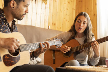 Frau singt beim Gitarrenspiel mit Mann zu Hause - LJF01879