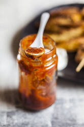 Hausgemachte rote Chilisauce in einem Glas auf dem Tisch - SBDF04449