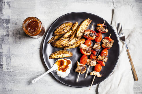 Gyros-Hähnchenspieße mit Tomaten, Paprika, Kartoffelspalten und Tzatziki auf dem Tisch - SBDF04451