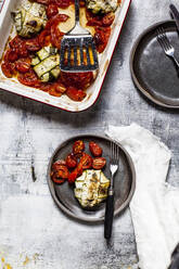 Gegrillte Tomaten mit Spinat und Feta-Käse gefüllte Zucchini-Ravioli im Teller mit Gabel auf dem Tisch - SBDF04456