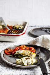 Mit Spinat und Fetakäse gefüllte Zucchini-Ravioli mit gegrillter Tomate im Teller auf dem Tisch - SBDF04457