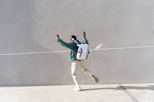 Mann mit Rucksack und Kopfhörern tanzt auf dem Fußweg - AFVF07814