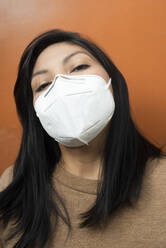 Woman with protective face mask against orange background - DSIF00221