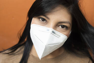 Woman against orange background in studio during pandemic - DSIF00222