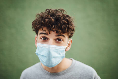 Young man with surgical mask against green background stock photo
