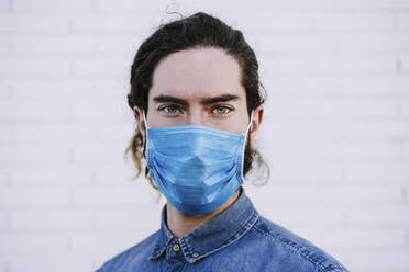 Young man with gray eyes wearing protective face mask during COVID-19 - EBBF01719