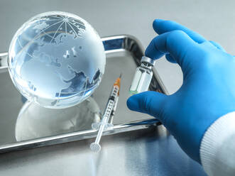 Nahaufnahme eines Arztes, der ein Fläschchen am Globus hält und eine Injektion in ein Tablett auf dem Tisch gibt - ABRF00796