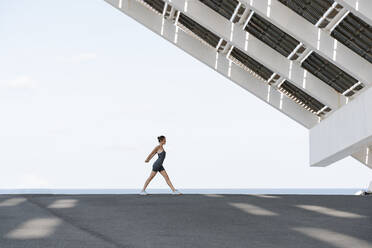 Sportswoman doing warm up exercise against clear sky - RDGF00256