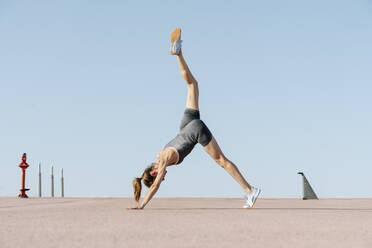 Mittlere erwachsene Sportlerin übt Yoga gegen den klaren Himmel - RDGF00273