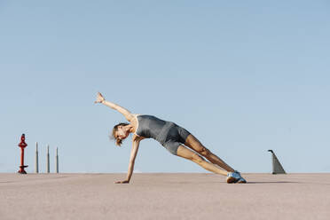 Weibliche Sportlerin übt Yoga und balanciert auf einer Seite - RDGF00274