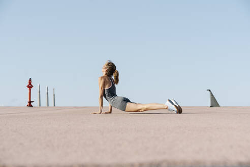 Eine Sportlerin praktiziert Yoga gegen den klaren Himmel - RDGF00276