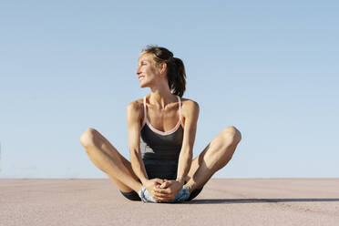 Female sportsperson looking away while sitting in cobbler pose - RDGF00284