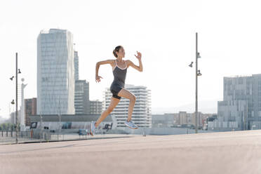 Lächelnde Sportlerin beim Laufen in der Stadt - RDGF00290