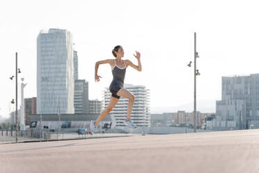 Smiling sportswoman running in in the city - RDGF00290