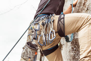 Sportlicher männlicher Alpinist beim Klettern an einer steilen Felswand an einem Sommertag - ADSF18802