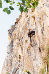 Sportlicher männlicher Alpinist beim Klettern am steilen Felsen an einem Sommertag - ADSF18804