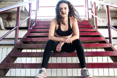 Sportliche Frau entspannt sich auf der Treppe des Stadions - CAVF91376