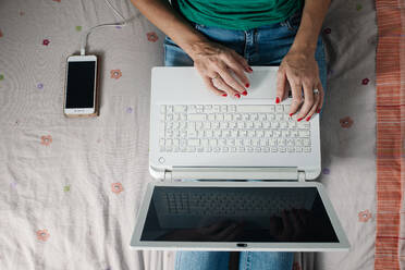 Frau arbeitet mit Laptop auf dem Bett - CAVF91388