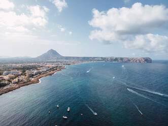 Drone view of motor boats floating in rippling water of blue sea near coastal city on sunny day - ADSF18834