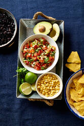 Zutaten für die Zubereitung von Chilaquiles - schwarze Bohnen, Tortilla-Chips, Mais und Salsa - ADSF18854