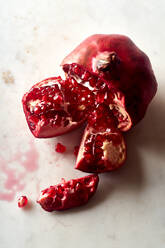 Fresh ripe halved pomegranate and seeds on white marble background - ADSF18938