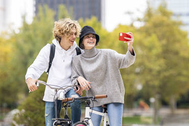 Freunde lachen, während sie im Park ein Selfie mit dem Handy machen - GGGF00453