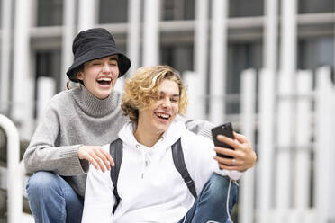 Junge Freunde lachen, während sie ein Selfie mit dem Handy machen - GGGF00468