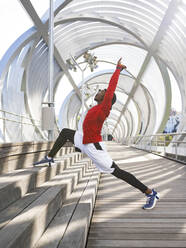 Male acrobat stretching while exercising on walkway - JCCMF00147