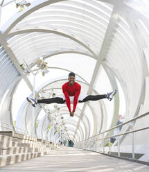 Acrobat jumping while doing the splits on walkway - JCCMF00149