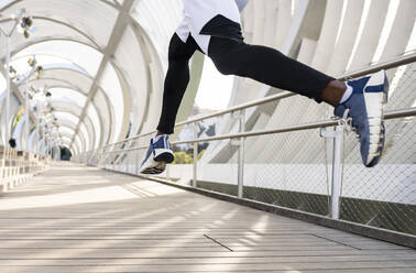 Athlete wearing sports shoe running on walkway - JCCMF00151