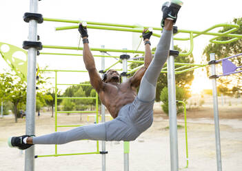 Male acrobat hanging on sports equipment at training ground - JCCMF00164