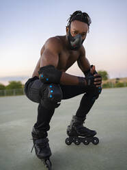 Sportsman wearing protective face mask and roller skate crouching on ground - JCCMF00169