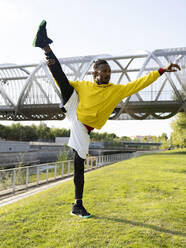 Sportler macht Spagat-Yoga im Stehen auf dem Gehweg - JCCMF00173