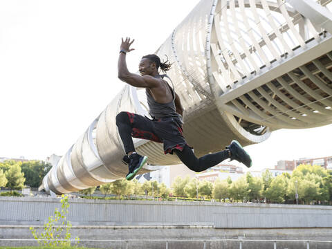 Smiling sportsman exercising while running against walkway stock photo