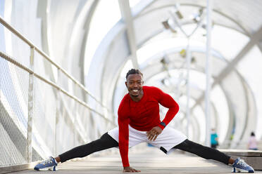 Smiling athlete doing splits while exercising on walkway - JCCMF00180