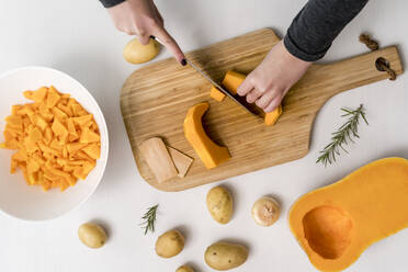 Hands of woman chopping squash on cutting board - MAUF03653