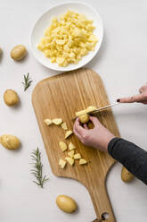 Hands of woman chopping potatoes on cutting board - MAUF03656