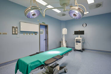 Zeitgenössische Operationssaal Interieur mit Couch unter glänzenden Lampen in der Nähe von professionellen Geräten im Krankenhaus - ADSF19032