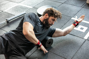 Männlicher Gewichtheber macht Bauchpressen beim Training im hellen Fitnessstudio - ADSF19037