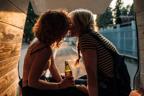 Junges lesbisches Paar küsst sich auf dem Rücksitz ihres Vans - CUF56608