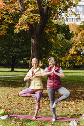 Reife Freundinnen üben gemeinsam Yoga im Herbstpark - VYF00343