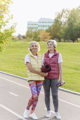 Lächelnde Freundinnen in Sportkleidung in einem öffentlichen Park an einem sonnigen Tag - VYF00350